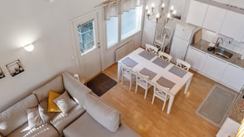 Ein stilvoller Wohnbereich mit Sofa, Esstisch, Stühlen, Küchenzeile und einer Kronleuchter.