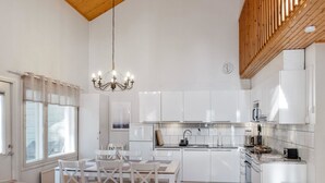 A modern kitchen with white cabinetry, a dining area with a table and chairs, and a chandelier.