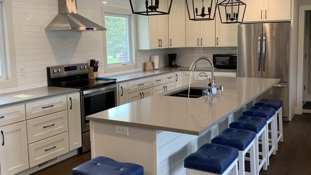A modern kitchen with white cabinetry, stainless steel appliances, and a central island with bar stools.