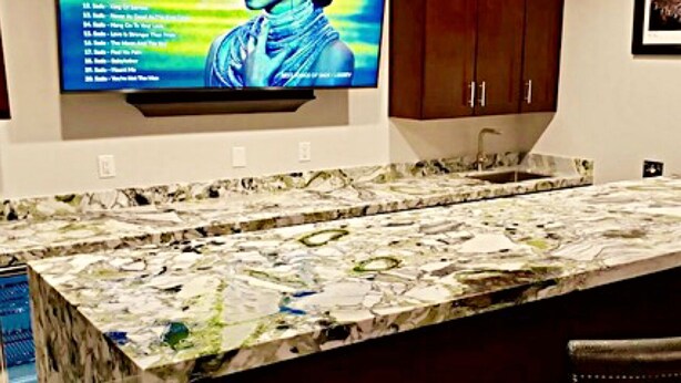 A kitchen with a marble countertop and a flat-screen TV mounted above it. - Five Bedroom Five Bath Residence  in Vegas  (Las Vegas)