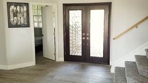 A hallway with a dark wooden door, a staircase, and a bed in the adjacent room. - Five Bedroom Five Bath Residence  in Vegas  (Las Vegas)