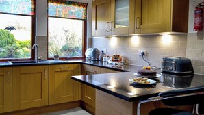 A kitchen with wooden cabinets, a black countertop, a toaster, and a window with a view of greenery.