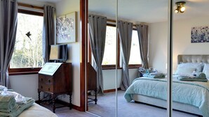 A bedroom with a bed, a dresser, a mirror, and a window with curtains.