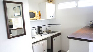 A compact kitchen with a microwave, coffee maker, and a small refrigerator. - Bleu Horizon Résidence by weekome (Les Abymes)