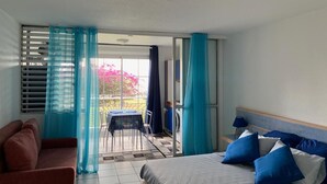 Quarto de hotel com cama, sofá, mesa e vista para o exterior.