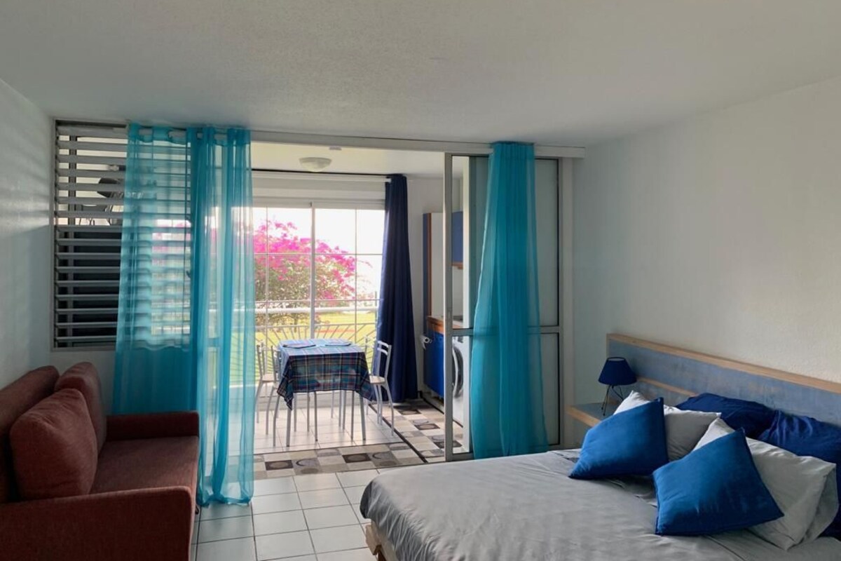 A hotel room with a bed, a sofa, a table, and a view of the outside.