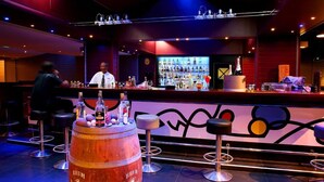 Uma área de bar com banquetas, balcão e um grande barril.