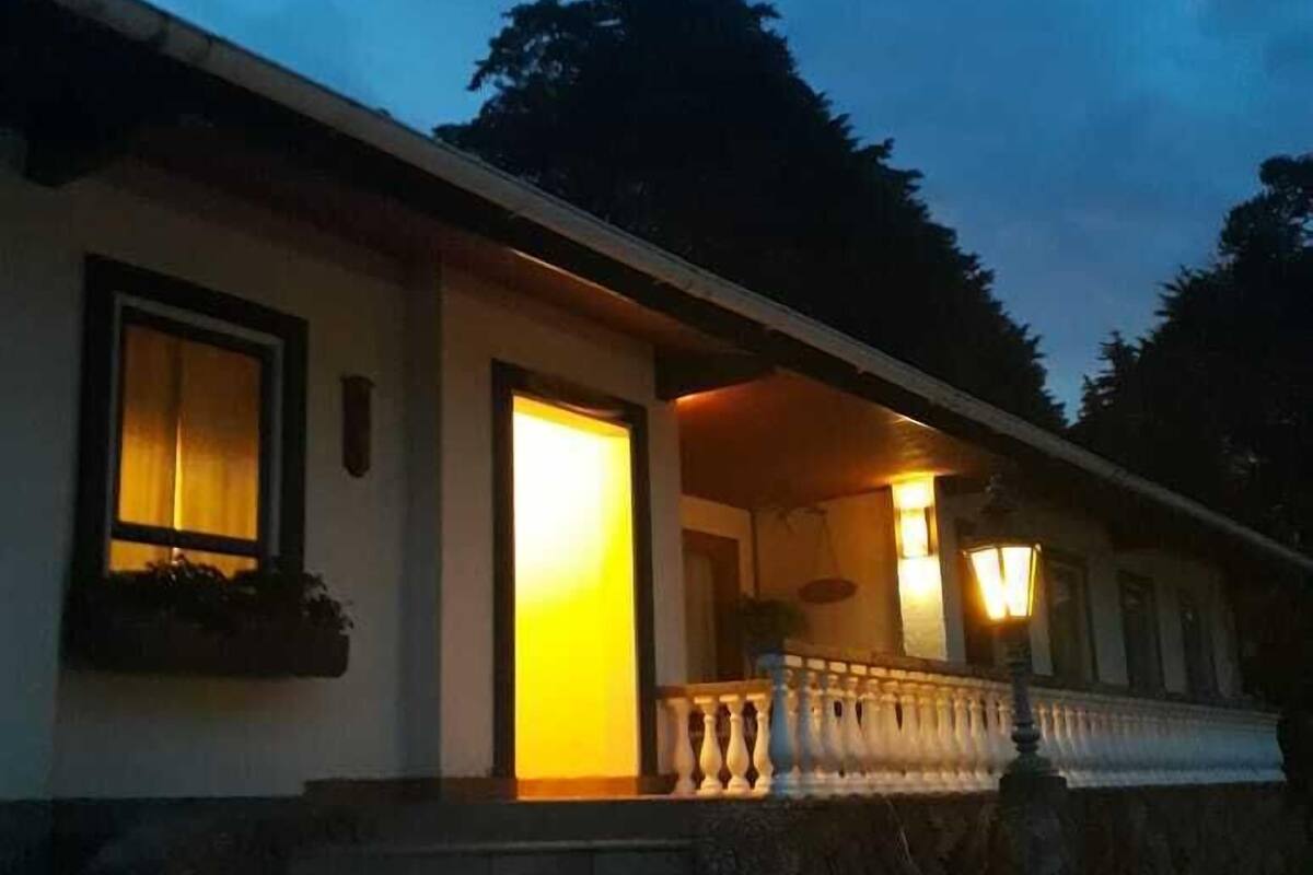 Una casa amb un porxo, uns escalons que porten a l'entrada i una porta encesa.