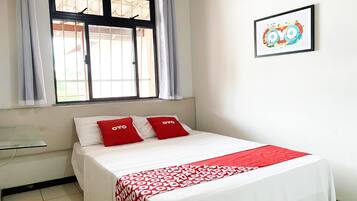 Una habitación de hotel con una cama, una ventana con cortinas, una mesita de noche y un cuadro en la pared.