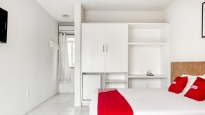 A modern hotel room with a large bed, white wardrobe, and a small desk. - OYO Praia Hotel Recanto do Tomé - Salvador (Salvador)