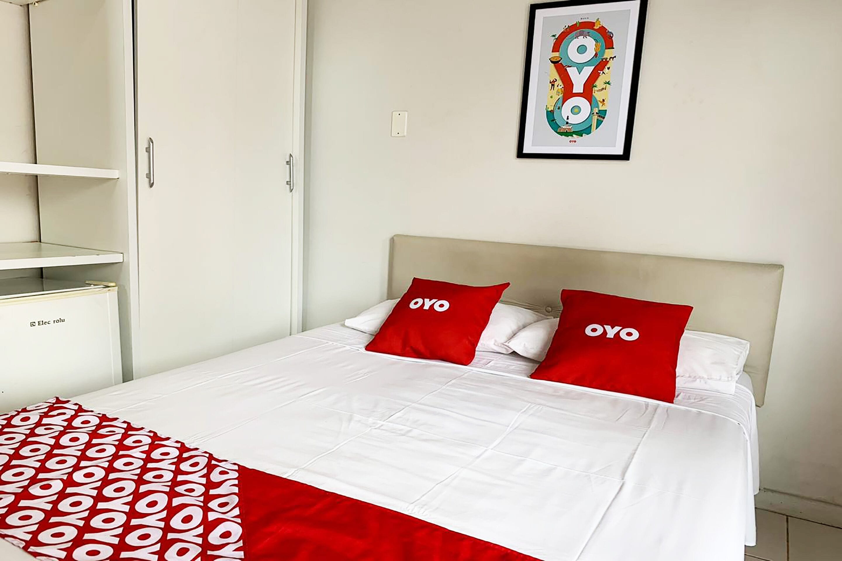 A hotel room with a bed, a wardrobe, and a framed artwork on the wall.