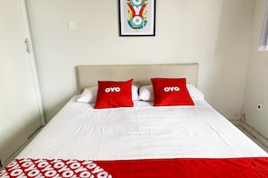 Una cama bien hecha con ropa blanca y dos almohadas rojas con la palabra "YOYO".