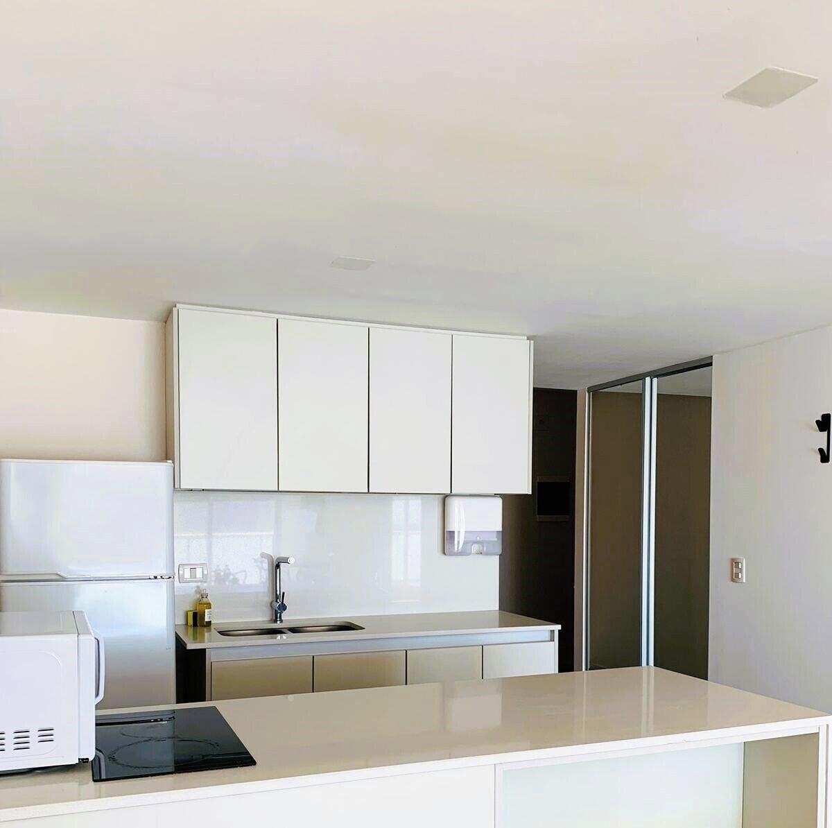 A modern kitchen with white cabinets, a built-in oven, and a sink.