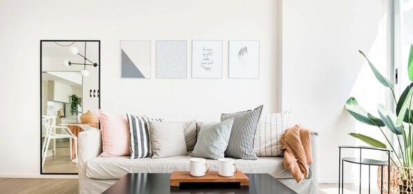 Un salon moderne avec un canapé, une table basse et des œuvres d’art encadrées accrochées au mur.