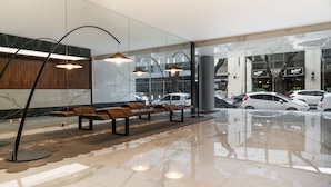 Un vestíbulo moderno con piso de mármol, bancos de madera e iluminación colgante.