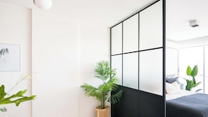 Un dormitorio moderno con una cama, un escritorio, una silla, una planta en maceta y un panel corredero shoji.