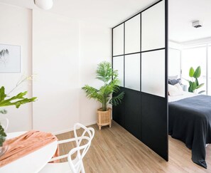 A modern bedroom with a bed, a desk, a chair, a potted plant, and a sliding shoji screen. - Top Rentals Belgrano (Buenos Aires)