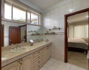 Un baño con dos lavamanos, un espejo grande y una zona de ducha.