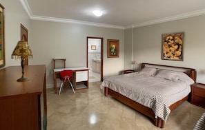 Un dormitorio con cama, escritorio, silla y mesita de noche.