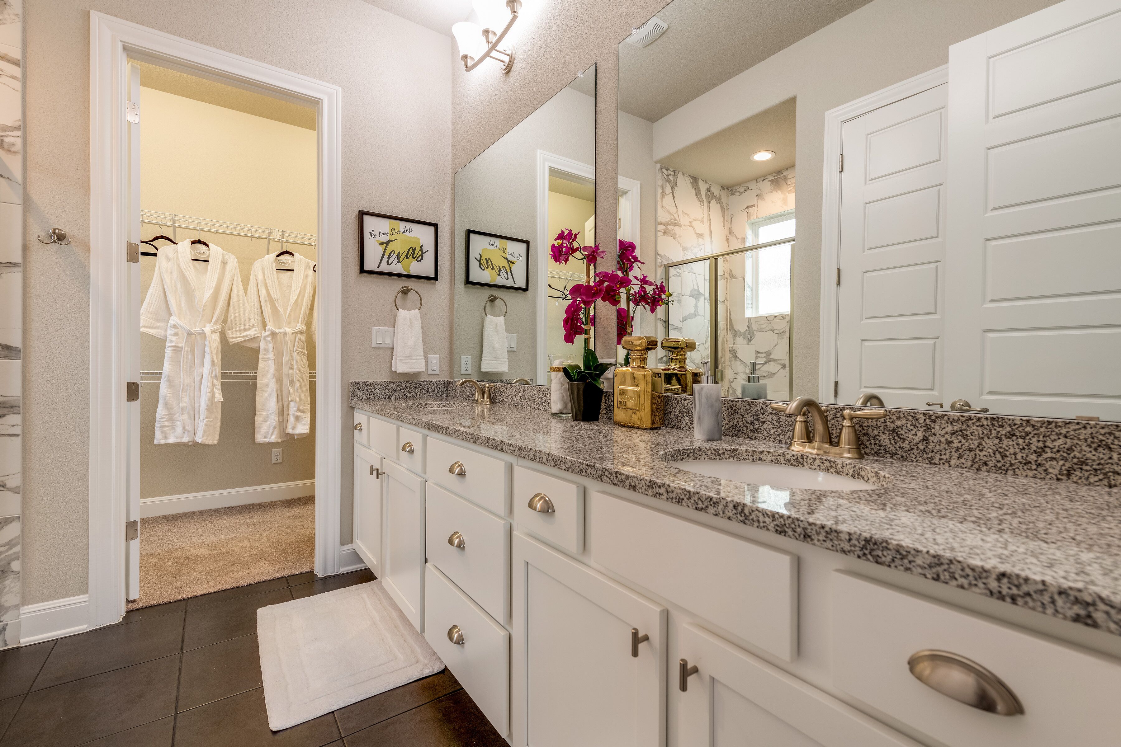 A bathroom with a double sink vanity, a large mirror, and a towel rack with white towels.