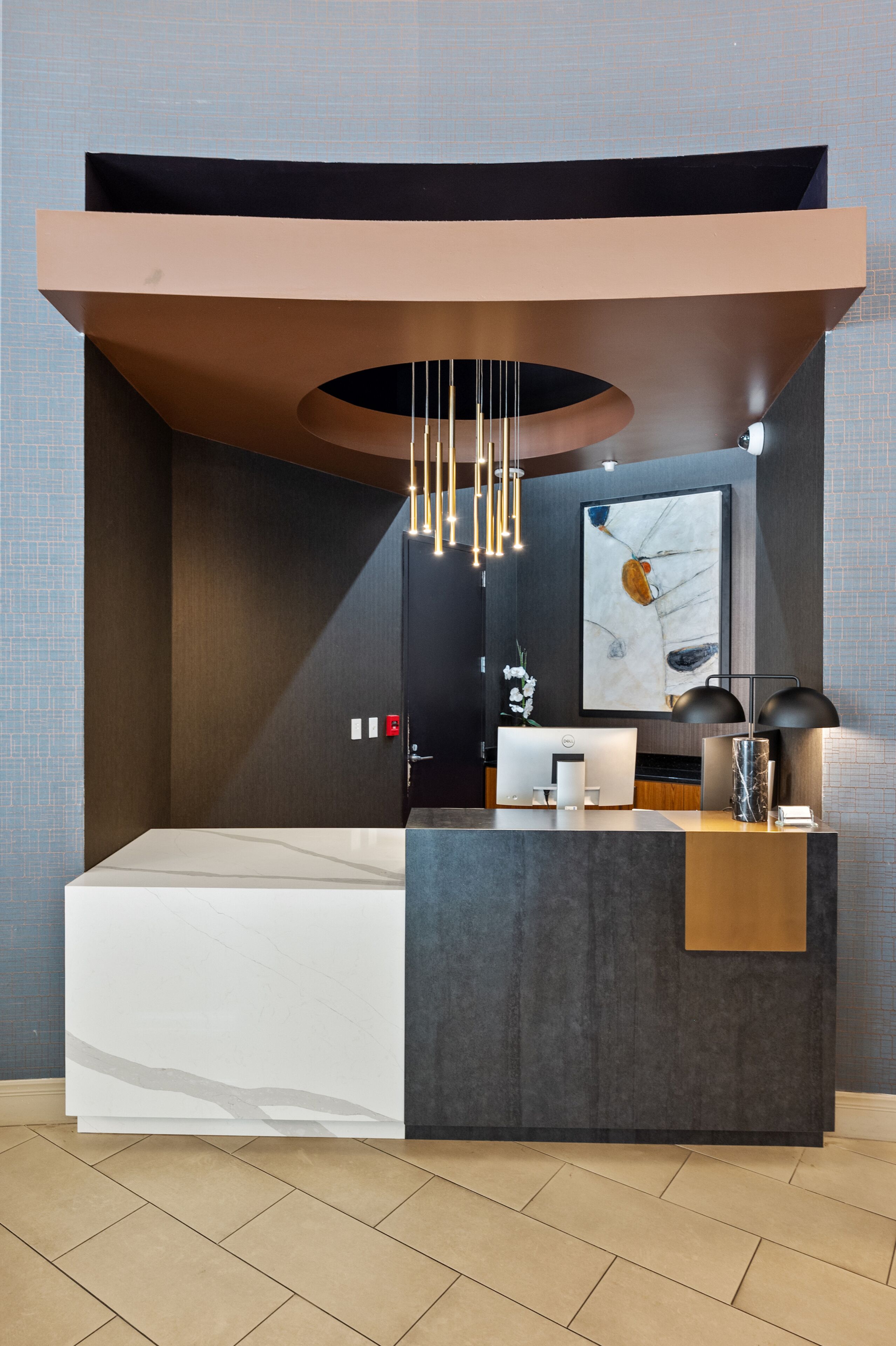 A modern hotel room with a large bed, a desk with a computer, a mirror, and a unique circular ceiling design.