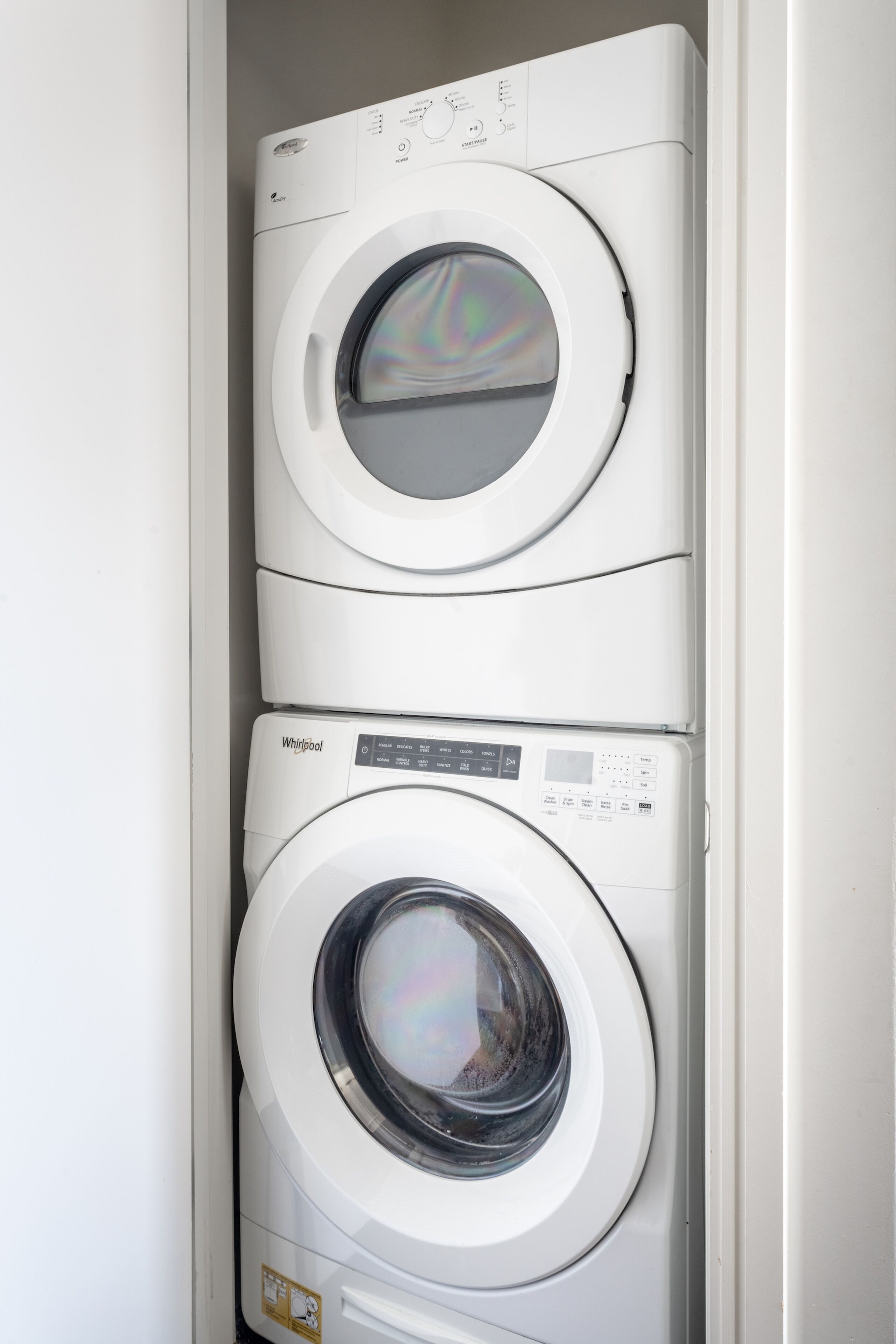 Two stacked front-loading washing machines in a white cabinet.