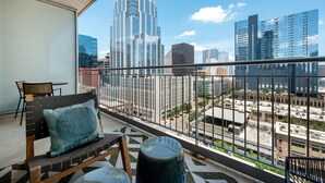 Un balcón con vistas a un paisaje urbano, que incluye edificios modernos y un cielo despejado.