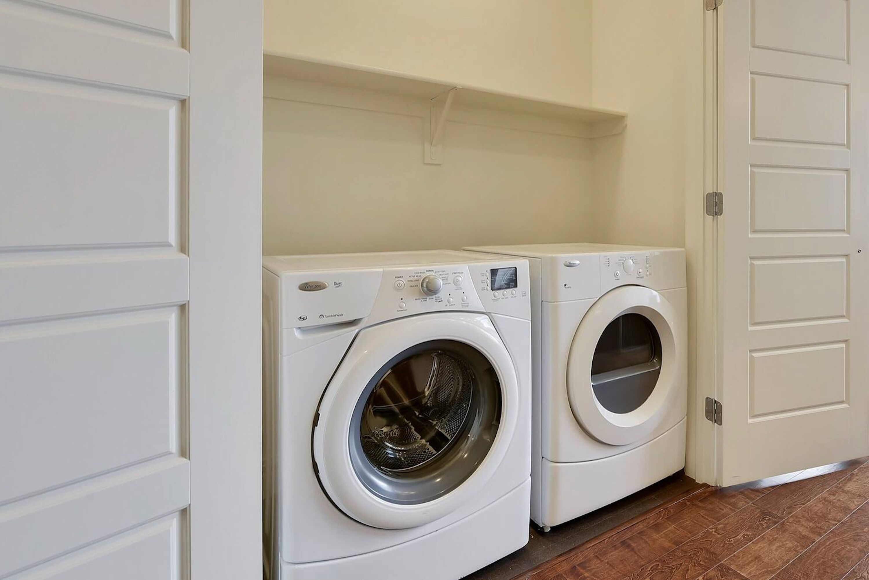 A laundry room with two front-loading washing machines and a door to the right.