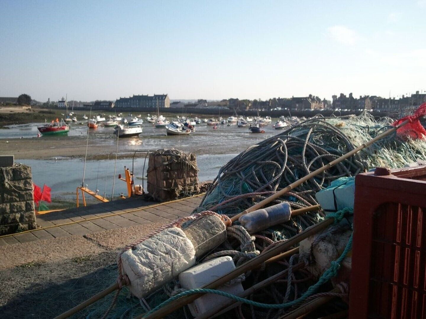 Ein Hafen mit Booten, Fischernetzen und einer Steinmauer.