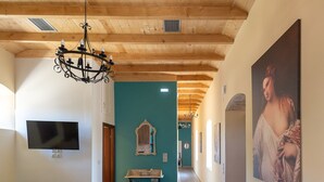 A long wooden dining table with benches, a chandelier, a flat-screen TV, and a large painting on the wall. - Villa Maria (Kefalonia)