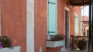 A building with a stone facade, a wooden pergola, and a large planter on the ground. - Villa Maria (Kefalonia)