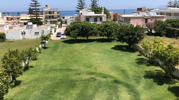 A residential area with houses, a grassy lawn, and a clear view of the sea. - Welcome to SEASIDE APARTMENT (agia marina)