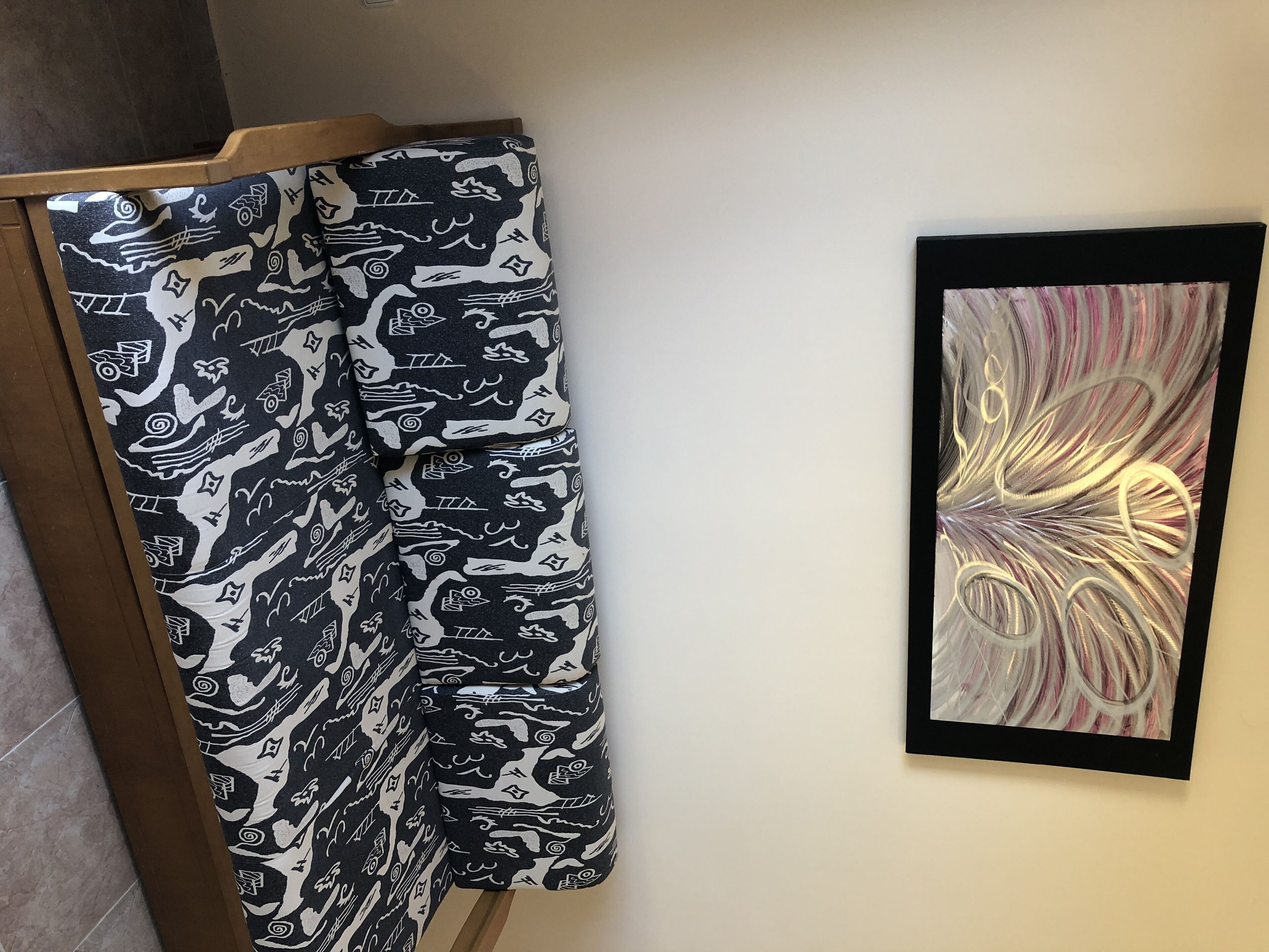 A room with a bed, a framed abstract painting, and a window.