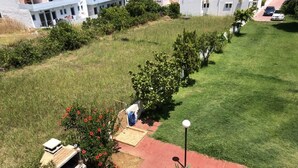 A residential area with a well-maintained lawn, a barbecue area, and a paved walkway. - Welcome to SEASIDE APARTMENT (agia marina)