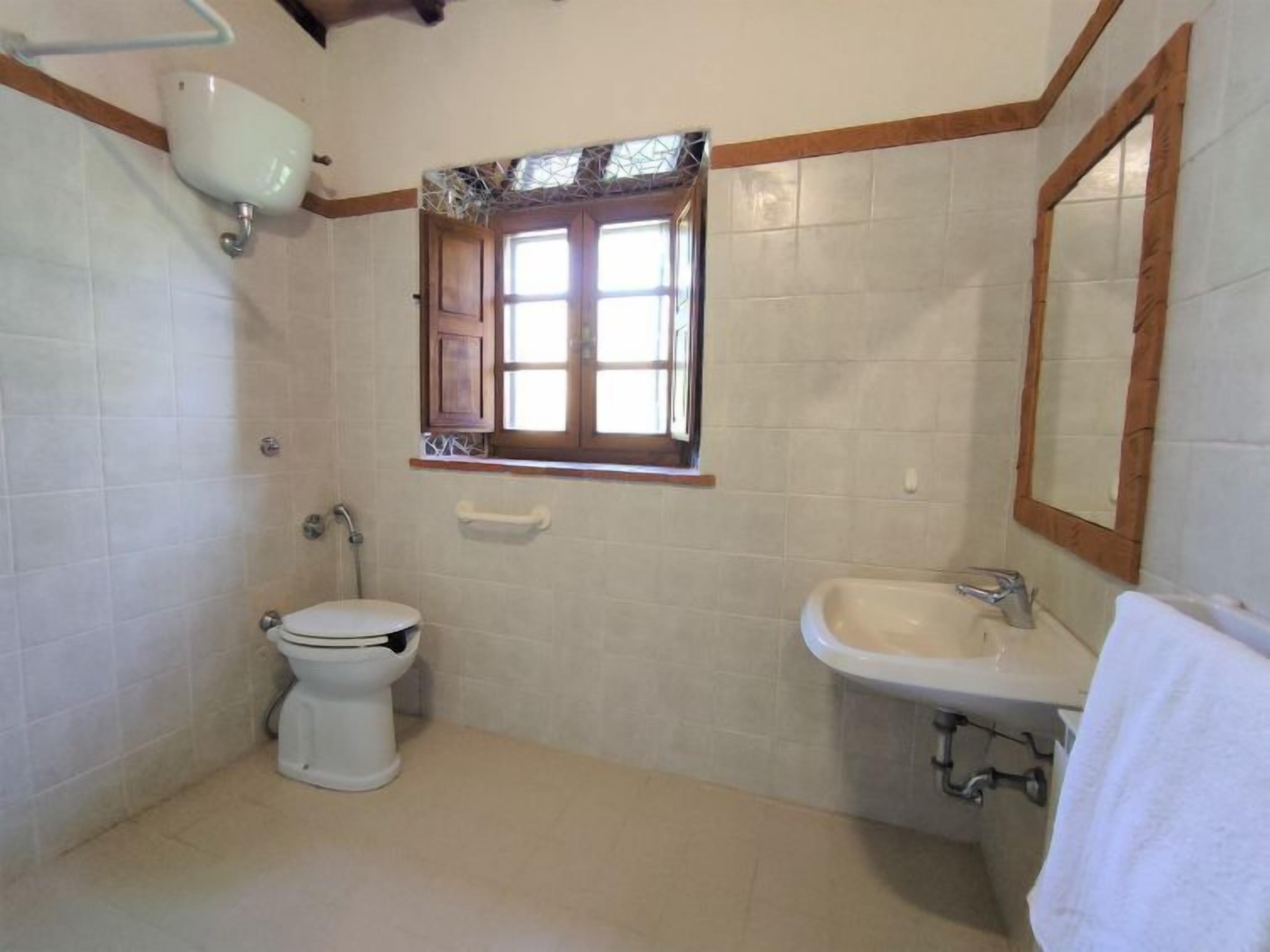 Een kleine badkamer met een toilet, een wastafel en een raam.