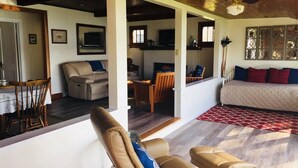 A spacious living area with a sofa, a dining table with chairs, and a kitchen visible through an open doorway. - Quiet Lakefront property on Cassadaga Lake WiFi & 2 car parking. (Cassadaga)