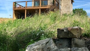 A brick house with a wooden deck and a large rock in the foreground.
