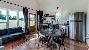 A modern kitchen with a dining area, large windows, and a cozy seating area.