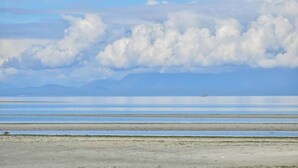 Paesaggio costiero con un'ampia spiaggia sabbiosa e acque calme.