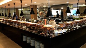 A buffet setup with multiple food stations, including hot and cold dishes, arranged on a long counter. - Magique Le Canton (Teresópolis)
