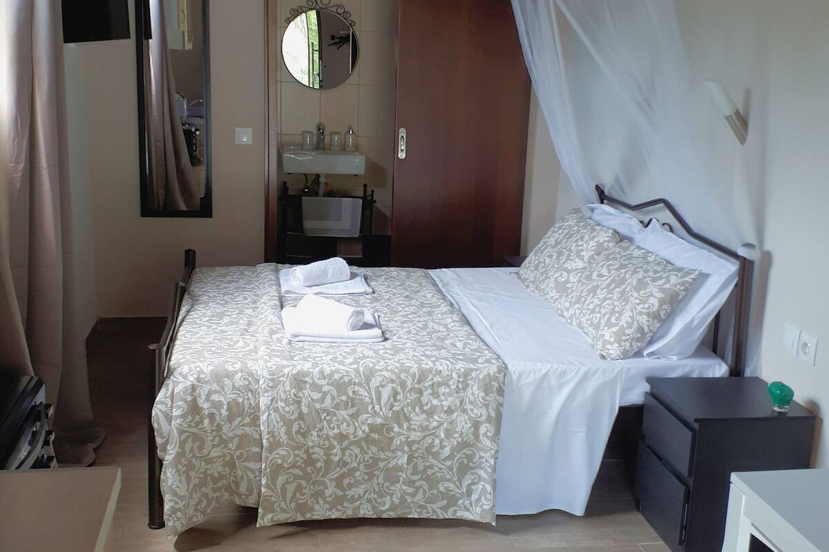 A bedroom with a bed, bedside table, and a mirror.