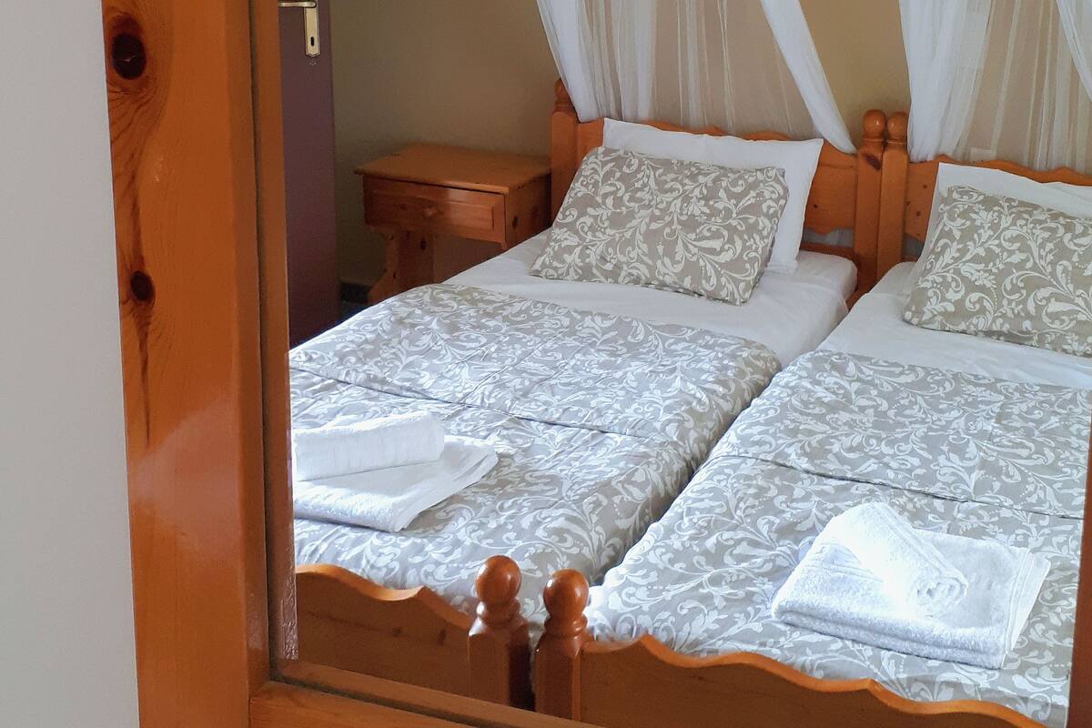 A double bed with a canopy, a wooden nightstand, and a mirror frame.
