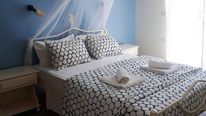 A bedroom with a bed, nightstand, and a window with curtains. - Antzela Apartments (Corfu)