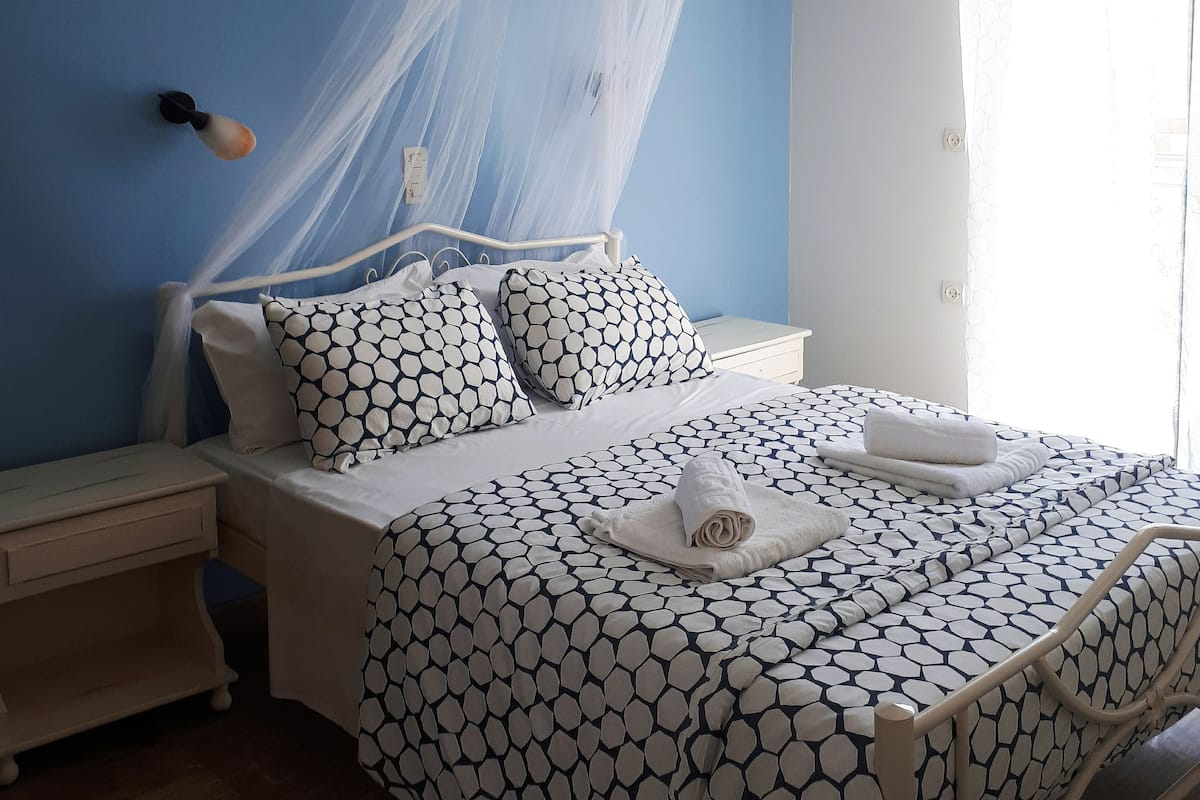 A bedroom with a bed, nightstand, and a window with curtains.
