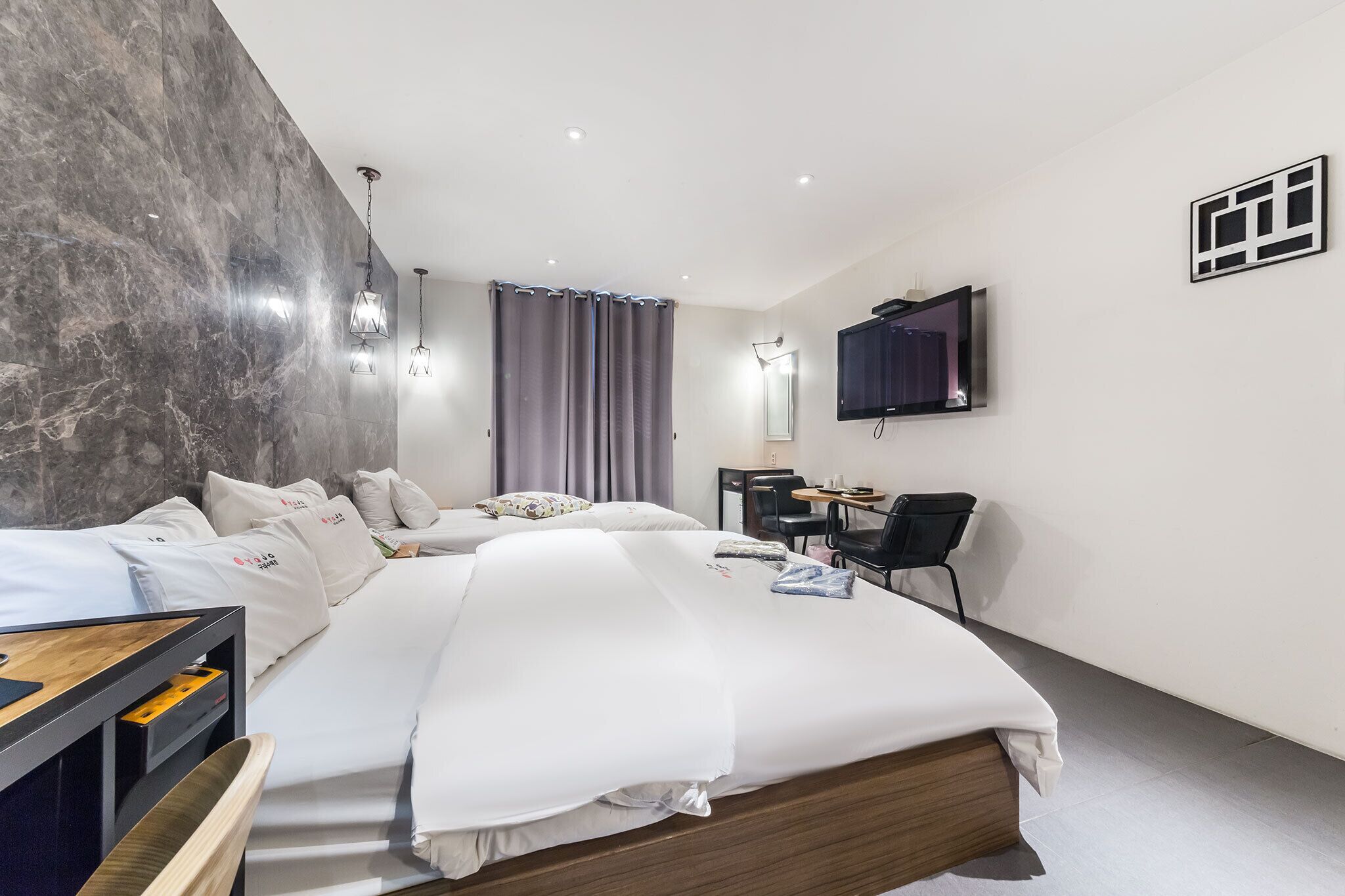 A modern hotel room with a large bed, a desk, and a flat-screen TV mounted on the wall.