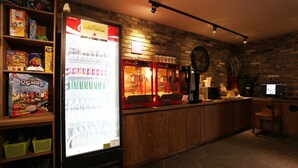 A bar area with a refrigerator stocked with beverages, a clock on the wall, and shelves with various items.