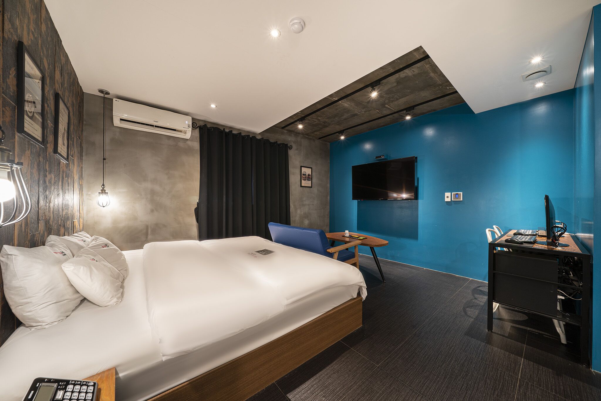 Een moderne hotelkamer met een groot bed, een bureau met een computer, een televisie en een airconditioner.