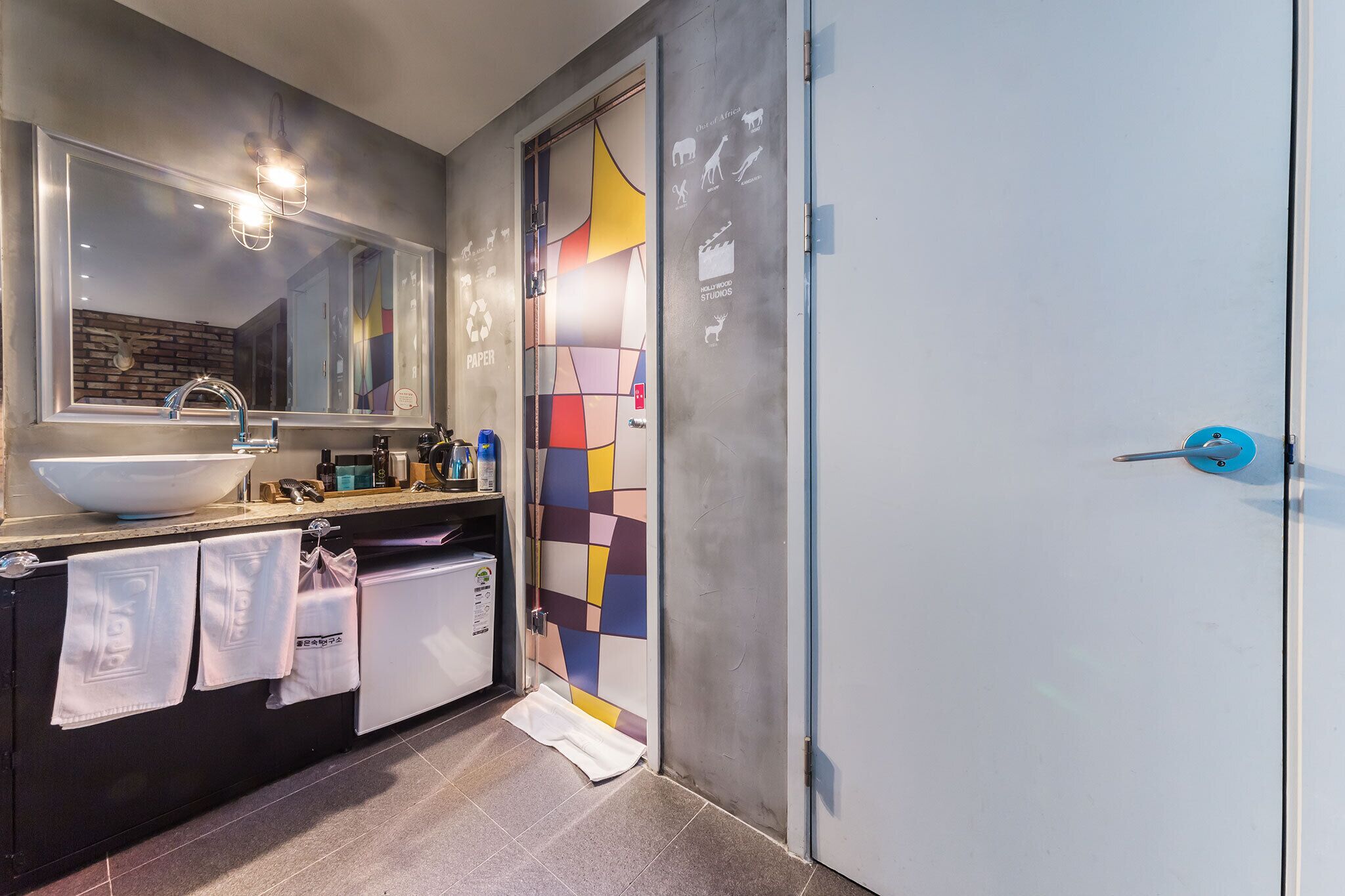 Een moderne badkamer met een grote spiegel, een wastafel en een handdoekhouder.