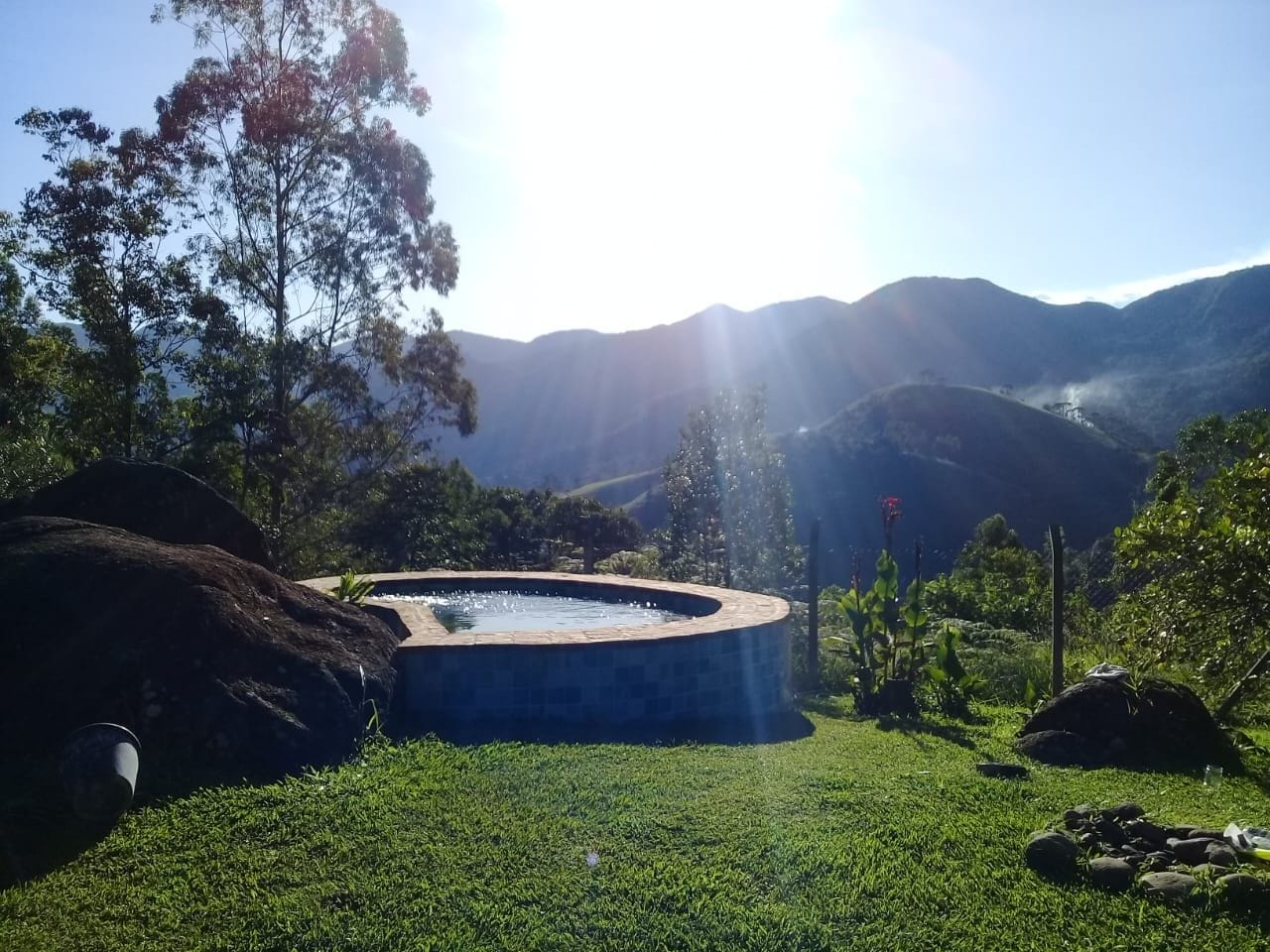 Un bain à remous entouré d’une pelouse, avec des montagnes en arrière-plan.