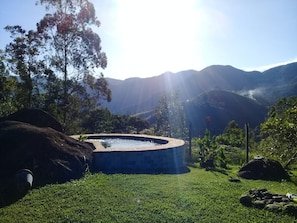 Un bain à remous entouré d’une pelouse, avec des montagnes en arrière-plan.